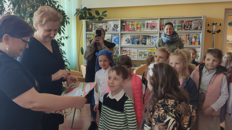 Zdjęcie kolorowe, przedszkolaki z życzeniami z okazji dnia bibliotekarza w bibliotece